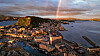 Panoramabilde av en kystby med havn, tett bebyggelse og ås i solnedgang. Ålesund.