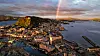 Panoramabilde av en kystby med havn, tett bebyggelse og ås i solnedgang. Ålesund.