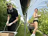 To personer står i et drivhus med bøtter og kasser mens de høster bær blant grønne planter.