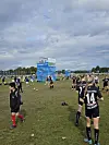 Ungdomsspillere står og varmer opp på en gressbane med Norway Cup-skilt i bakgrunnen.