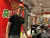 En butikkansatt står ved kassen i en Ringo-butikk med leker og hyller i bakgrunnen.
