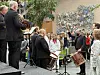 Et brassband spiller foran tilskuere i en utegård med fargerik veggkunst.