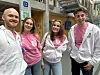 Fire unge mennesker står side om side innendørs, kledd i rosa og hvite hettegensere.