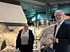 To personer står i et museumsrom med stein, trapp og lyse utstillinger om verdensrommet.