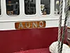 Nærbilde av en rød og hvit båt med navneskiltet AUNO og tykke tau ved kaia.