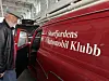 En eldre mann står ved siden av en rød veteranbil med teksten Storfjordens Automobil Klubb.