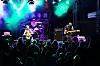 Et rockeband spiller på scene foran en tett samlet publikumsmengde i mørket.