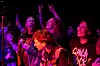 Publikum står tett foran en scene og jubler under en hardrock-konsert med rosa og lilla scenelys.