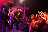 Et hardrockband spiller på en liten scene mens publikum rekker hendene i været foran scenen.