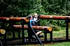To barn sitter og klatrer på rustne jernrør i et grønt skogholt.