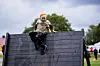 Et barn sitter på toppen av en mørk trehindring utendørs.