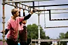 To ungdommer står ved et utendørs klatrestativ og holder i metallstenger.