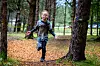 Et barn løper på en skogssti mellom trær, med gjørme og gult sperrebånd i bakgrunnen.