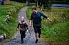 To personer går på en grussti omgitt av grønt gress og høyt siv.