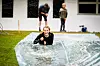 Et barn ligger på magen på en plastdekket vannsklie ute på en gressplen.