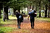 To personer går bortover en parksti dekket av høstløv, begge bærer store bildekk.
