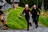 To barn løper på en grusvei med en voksen delvis synlig til venstre.