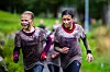 To personer løper side om side på en våt og gjørmete skogssti.