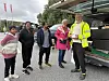 En gruppe mennesker står sammen ved en åpen varebil på en parkeringsplass.