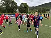 En fotballspiller i blå Aafk-drakt går sammen med flere unge jenter på en kunstgressbane.
