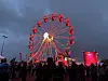 Festivalpublikum står foran et opplyst pariserhjul under en mørk kveldshimmel.