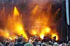 Konsertscene med Tobias Sten, oransje scenelys, røyk og et tett publikum foran scenen.
