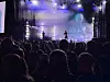 Silhuett av en artist på en opplyst scene foran et publikum i en mørk konsertsal.