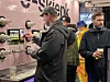 Flere personer står ved en rekke ølkraner, mens en mann tapper øl i et glass.