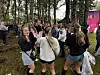 Unge mennesker danser og snakker sammen i et skogsområde med flere deltakere i bakgrunnen.