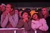 Flere konsertgjengere står tett sammen ved en sperring foran scenen.