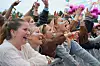 Unge festivalgjengere jubler med hendene i været ved en konsertscene.