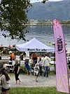 Barn og voksne ved en aktivitetsplass med telt og rosa banner ved fjorden.