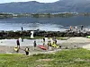 Barn og voksne i redningsvester samles ved kajakker på en steinete strand.