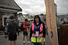 Kvinnelig løper med startnummer står foran et Backyard Ultra-banner ved sjøen i Ålesund.