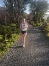 En løper i treningstøy løper mot kameraet på en grussti omgitt av trær og grøntområder.