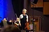Ung fiolinist med fiolin står foran et orkester på en scene.