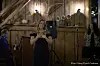 Sanger holder mikrofon på en liten scene, med musikere og publikum rundt seg.