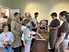 En gruppe mennesker står rundt en disk med kanelsnurrer og annen bakst i et innendørs bakeriutsalg.