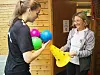 To personer står i et gymsalrom med fargerike baller og en gul kjegle.