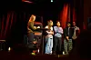 Gruppe på scenen med røde tepper, keyboard og scenebelysning.