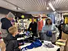 Kunder og ansatte står ved kassen i en butikk med klær og varer utstilt.