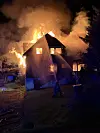 Et bolighus står i brann med flammer og tett røyk mot nattehimmelen.