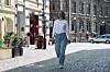 En kvinne går alene på en brosteinsgate mellom bygninger i et bysentrum.