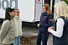 Fire kvinner snakker sammen utendørs foran en hvit arrangementsvogn.