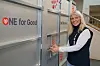 Kvinne ved siden av metallbeholdere merket «ONE for Good».