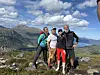En gruppe turgåere står samlet på et fjellplatå med Sunnmørsfjell og fjordlandskap i bakgrunnen.