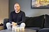 Uidentifisert mann sitter i en mørk sofa i en moderne stue med lys på bordet.