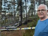 Mann i blå genser ved politisperrebånd i et skogsområde
