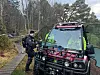 Person ved et svart terrengkjøretøy på en skogssti i høstlig skog.