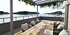 Overbygd restaurantterrasse med dekket bord, stoler og utsikt over fjorden.